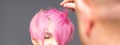 Hairdresser with hands is checking out and fixing the short pink hairstyle of the young white woman in a hair salon. Royalty Free Stock Photo