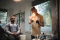A delightful barber spraying fire flames with a hairspray and tools for beard shave on a barbershop background.