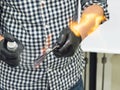 Hairdresser heating the blade of old fashioned straight razor under stream of fire for smoother shaving.