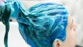 Hairdresser holds client& x27;s long blue hair in hand while washing hair after process of dyeing hair in beautiful dark blue