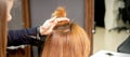 The hairdresser holds a strand in hand between fingers of the female hair. Examination of the hair of the young woman in