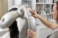 Hairdresser include hair dryer dries young girl& x27;s hair. Portrait of a girl in a beauty salon. The procedure of Royalty Free Stock Photo