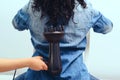 Hairdresser makes curly hairstyle for woman. Haircare concept. Woman styling her curly hair with hairdryer with special diffuser Royalty Free Stock Photo