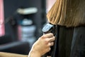 Hairdresser makes haircut to a girl in with long blonde hair. Hairdresser hands holding Royalty Free Stock Photo