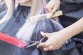 Hairdresser makes haircut to a girl in with long blonde hair. Hairdresser hands holding scissors Royalty Free Stock Photo