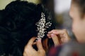 Hairdresser makes hairstyle to woman, puts brooch on hair