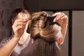 Hairdresser making a coiffure with topknot to a model