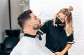 Hairdresser with mask shaving a man using an electric machine Royalty Free Stock Photo