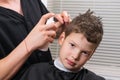 The hairdresser moistens the boys hair with a sprayer to do the haircut Royalty Free Stock Photo