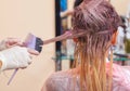 The hairdresser paints the woman`s hair in white, apply the paint to her hair