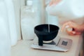 Hairdresser Poring hair Dye Developer in Mixing Bowl on a Scale