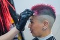 The hairdresser removes excess dye from the skin of a female with a cotton pad.Asian woman with a short haircut in a Royalty Free Stock Photo