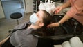 Hairdresser hands in blurred motion wash hair of female client in medical face mask.Quarantine reopening of beauty salon Royalty Free Stock Photo