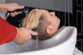 The hairdresser's hands wash the client's hair with rain and water over the sink before the haircut close-up