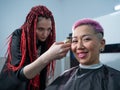 The hairdresser shaves the temple of a female client. Rear view of a woman with short pink hair in a barbershop.