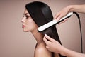 Hairdresser straightening long hair with hair irons