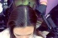 Hairdresser straights dark brown hair of beautiful woman using hair tongs in beauty salon. Top view.