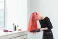 Hairdresser, style, people concept - woman is blowing dry her colored hair Royalty Free Stock Photo