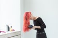 Hairdresser, style, people concept - woman is blowing dry her colored hair Royalty Free Stock Photo