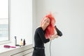 Hairdresser, style, people concept - woman is blowing dry her colored hair Royalty Free Stock Photo