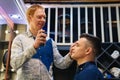 the hairdresser styling a brunette man and spraying hairspray in a barbershop Royalty Free Stock Photo