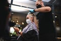 Hairdresser stylist working with compliance with quarantine safety measures when dyeing salon customer`s hair