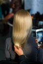 Hairdresser takes pictures on the smartphone result of hair coloring model Royalty Free Stock Photo