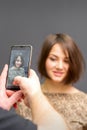 The hairdresser takes pictures of a woman finished short hairstyle on dark background. Royalty Free Stock Photo