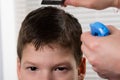 The hairdresser to the boy moisturizes his hair and does his hair