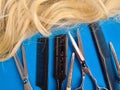 Hairdresser tools comb scissors and hair on blue background Royalty Free Stock Photo