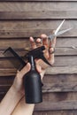 Hairdresser tools on a wooden background in the hands of a master. Dark tint. Protective spray, comb and hair scissors Royalty Free Stock Photo