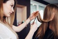 Hairdresser trimming the split ends of female customer sitting with long hair covering her face in beauty salon Royalty Free Stock Photo