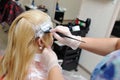 The hairdresser uses a brush to apply the dye to the hair, for d