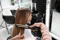 Hairdresser using straightener to style client`s hair