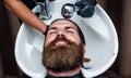 Hairdresser washes client man head in barbershop, hair care
