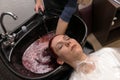 Hairdresser washes the client woman`s head on a special sink after dyeing hair in the hairdresser`s salon