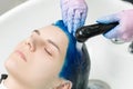 Hairdresser washes client& x27;s head with sapphire hair color after hair coloring process. Washing hair with shampoo in sink