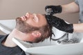 The hairdresser washes the head of the young man with shampoo after haircuts in the hairdresser.Men`s haircuts and hair care