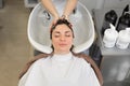 Hairdresser washes her hair with shampoo and massages the head of a young woman in a barber salon Royalty Free Stock Photo