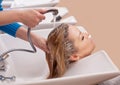 Hairdresser washes the shampoo off the hair to a young blonde girl, in a beauty salon.