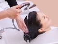 hairdresser washes the shampoo off the hair to a young girl, brunette