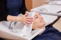 The hairdresser washes the shampoo off the hair to a young girl