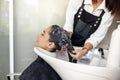 Hairdresser washes woman`s hair, side view Royalty Free Stock Photo