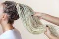 A hairdresser weaves dreadlocks to a beautiful young girl