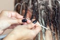 A hairdresser weaves dreadlocks to a beautiful young girl in a hairdresser`s. Professional hair care and creating hairstyles