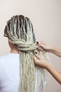 A hairdresser weaves dreadlocks to a beautiful young girl