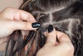 A hairdresser weaves dreadlocks to a beautiful young girl