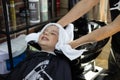 The hairdresser wipes the hair of a boy child with a white towel in the hairdressing salon. The boy smiles as the Royalty Free Stock Photo