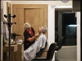 hairdresser, a woman, cutting the hair of a male client in a hairdressing salon wearing facemask protective equipment Royalty Free Stock Photo