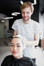 Hairdresser wrapping towel on customer`s head. Brunette woman getting hair treatment in a salon.